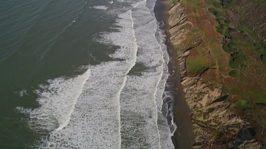 Aerial landscape of a sea with waves crashing on the mountainous and rocky shores