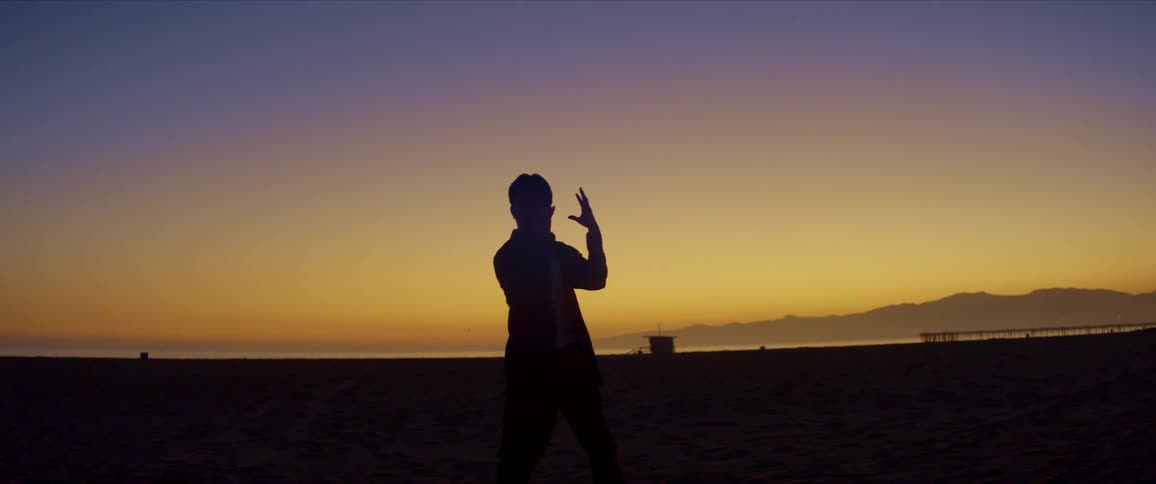 Silhouette of a man dancing in the beach at sunset