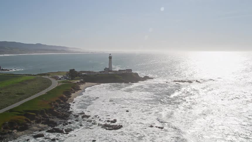 The lone lighthouse stands sentinellike on a rocky outcropping guiding ships away from the jagged coastline