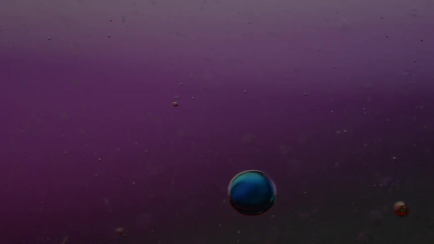 Yellow and blue droplets fall into clear liquid