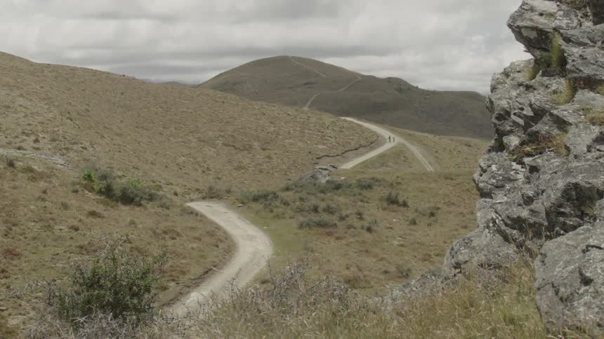A winding dirt hiking trail cutting through a hilly grass covered landscape