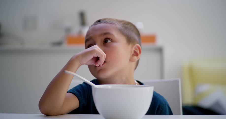 A child with a bowl in front, looks camera left