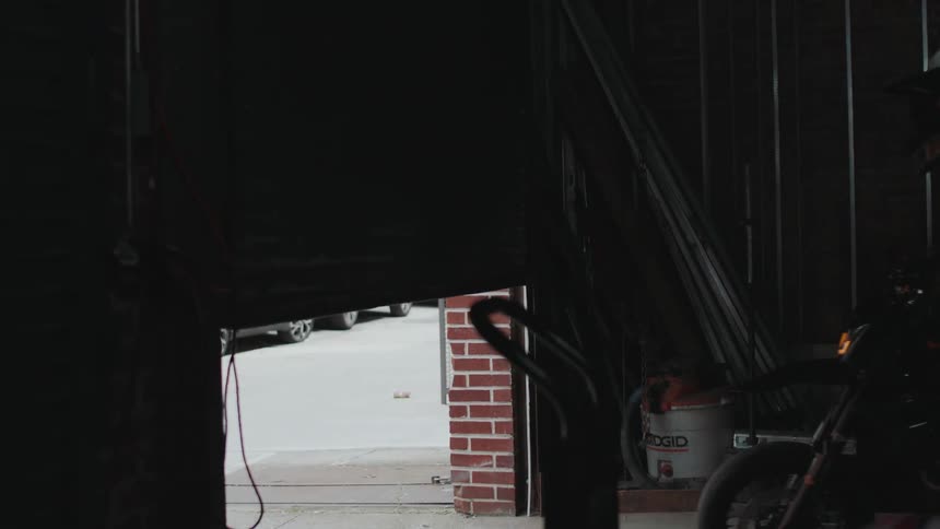 A man pushes his motorcycle out of the garage