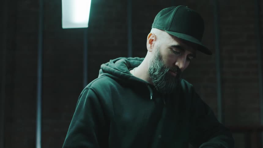 A bearded man in a cap is using a tool to fix a motorcycle handlebar
