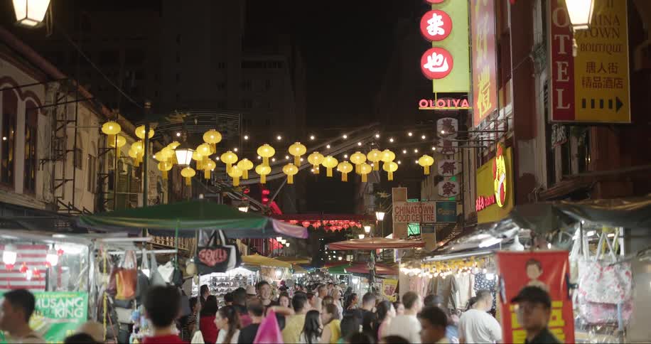 A busy asian street market with many lights and signs crowded with people
