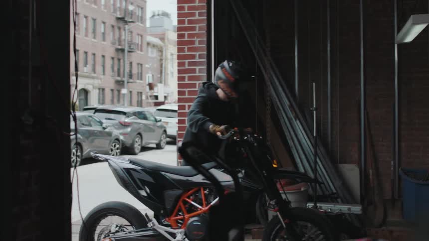 A clip of a person pushing a motorbike into a garage