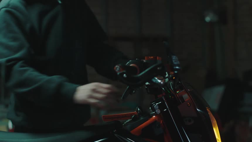 A man tests the controls on a motorcycle in his shop