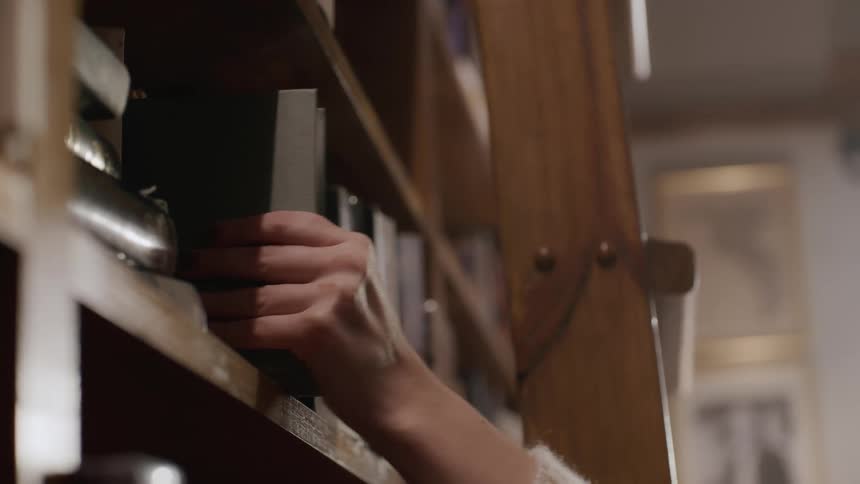 Womans hand removing a book from a shelf