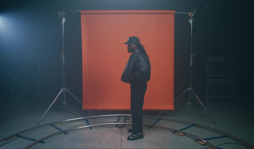 Man wearing jacket stands in front of red backdrop in a photography studio