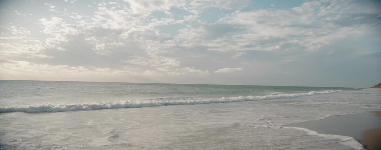 Ocean waves breaking and splashing as they come to shore on a sandy beach