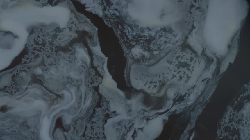 Light and dark liquids swirl together making patterns