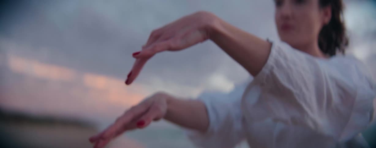 Woman standing on the beach on a windy day gestures with her hands