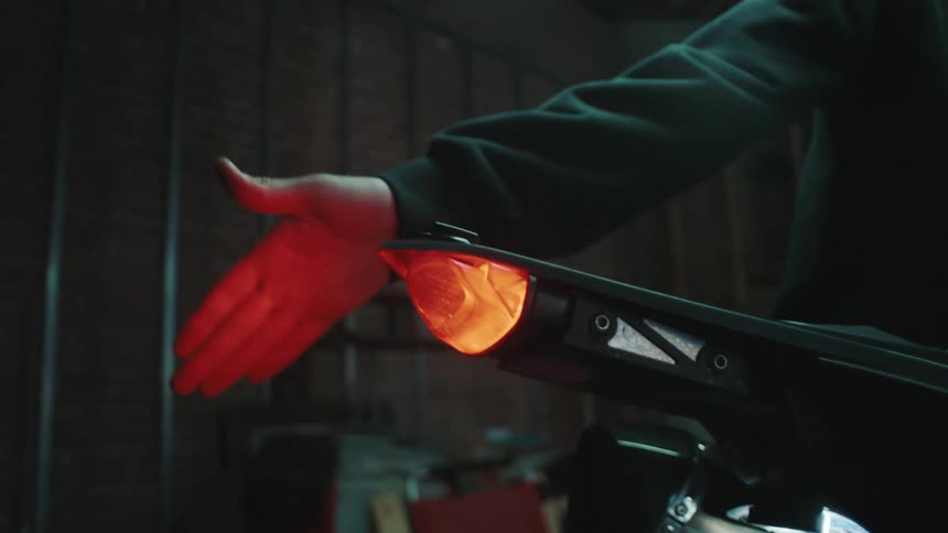 Man checking the taillight of a motorcycle in a garage