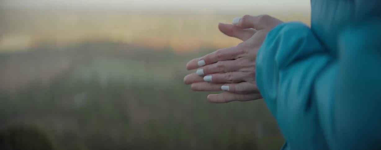 Woman standing outdoors rubs her hands to warm them