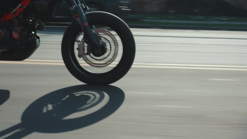 Motorcyclist rides motorcycle past city intersection on a sunny day