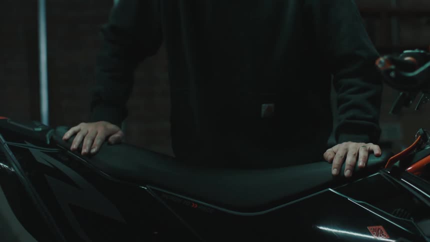 Man fitting a leather seat onto a motorcycle