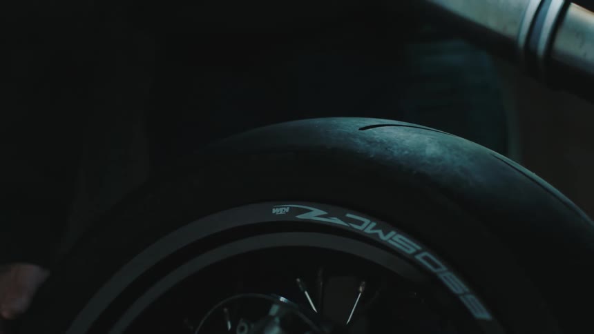 A man checks the rear tire treads of a motorcycle