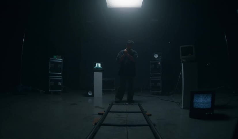A man stands in a room with televisions and other equipment