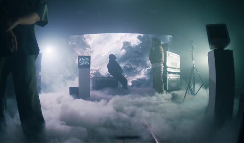Smoke flows across floor between televisions and men on a set