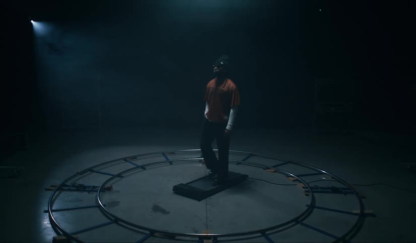A man is walking slowly on a treadmill in a dark indoor environment