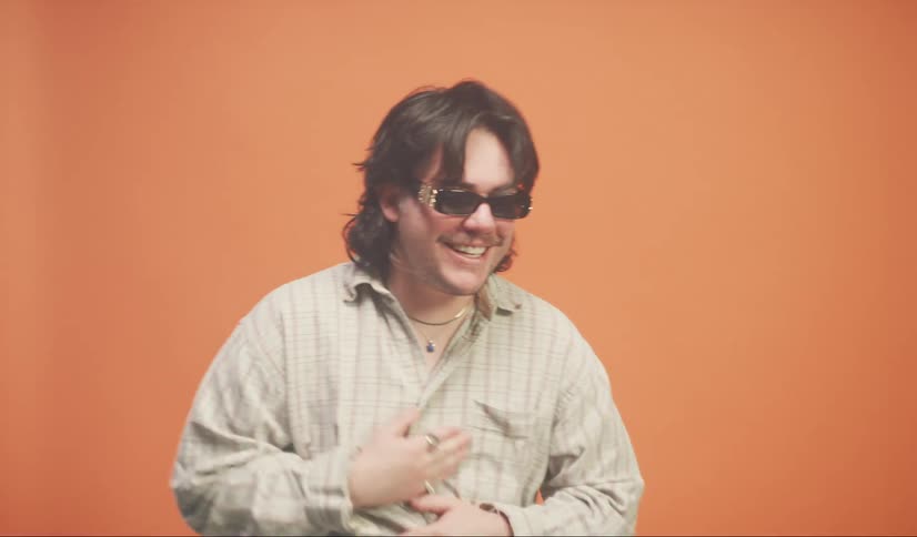 Portrait of a smiling man placing his hand on his chin against an orange background