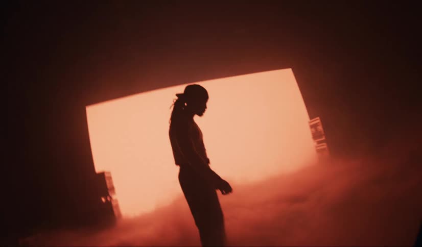 Model inside a studio with low lighting and a red screen in the background and abstract smoke in the environment