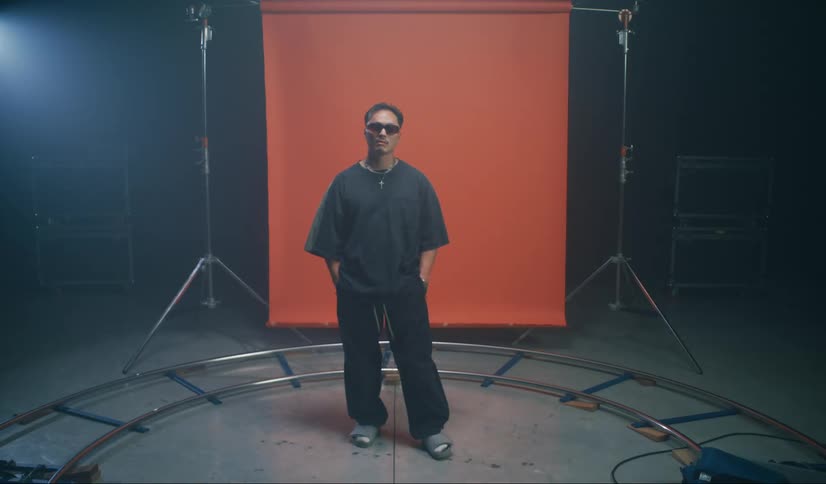 Male model turns while posing in front of backdrop on a set