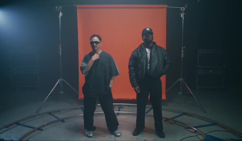 Two men in a circle in a studio with an orange banner in the background