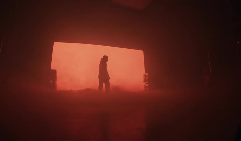 Silhouette of a person inside a studio with abstract smoke and a red screen in the background