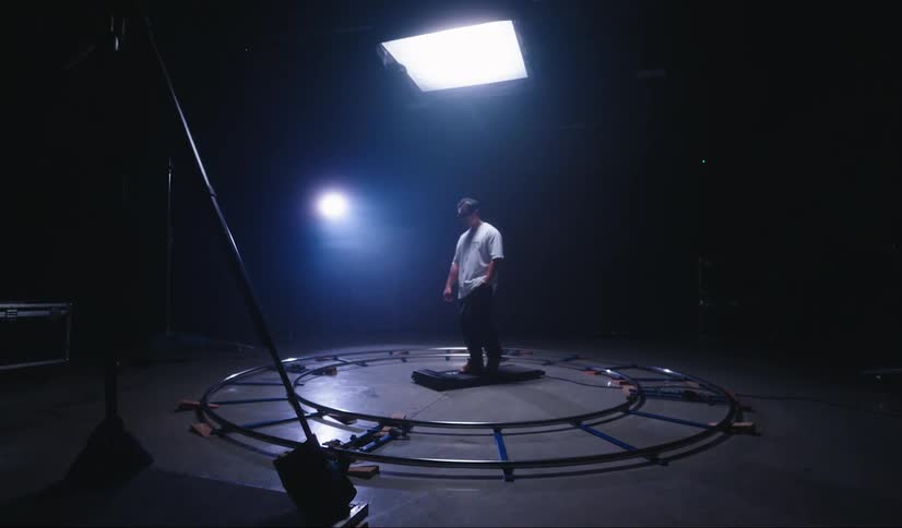 Man walks on treadmill in studio set in area surrounded by a camera track