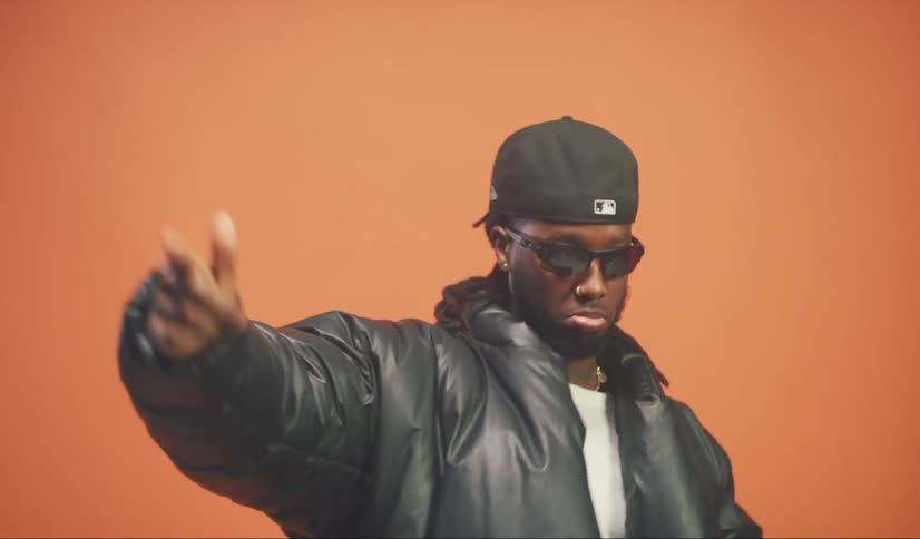 A man wearing a hat and sunglasses is rapping and moving to the beat