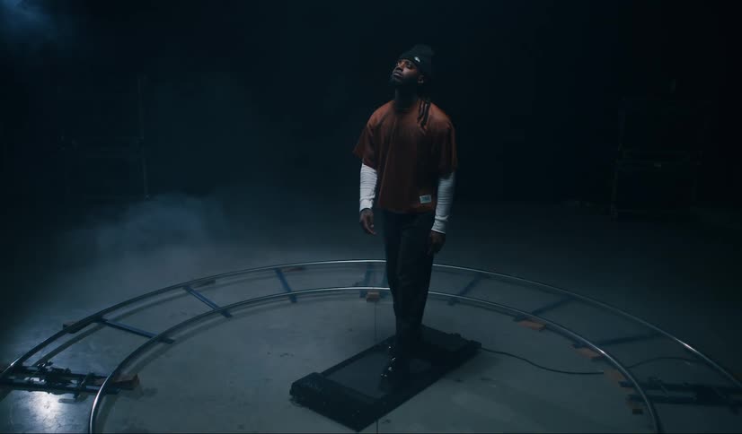 Man walks on small treadmill in center of empty camera track on a film set