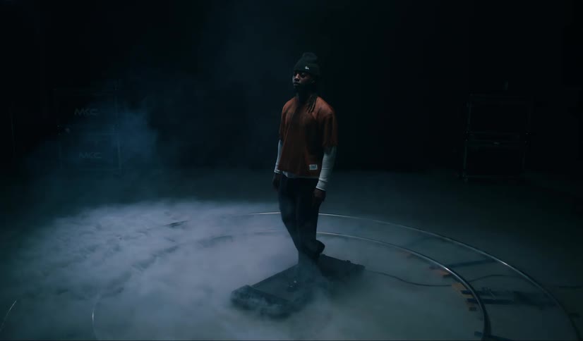 A man walks on a treadmill surrounded by smoke inside a dimly lit room