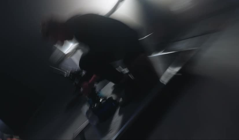 Three blurred people inside a lowlit studio working with film equipment