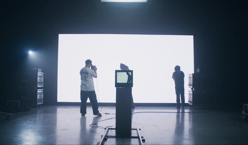 Two models in a movie studio with a cameraman filming them against a flickering white screen