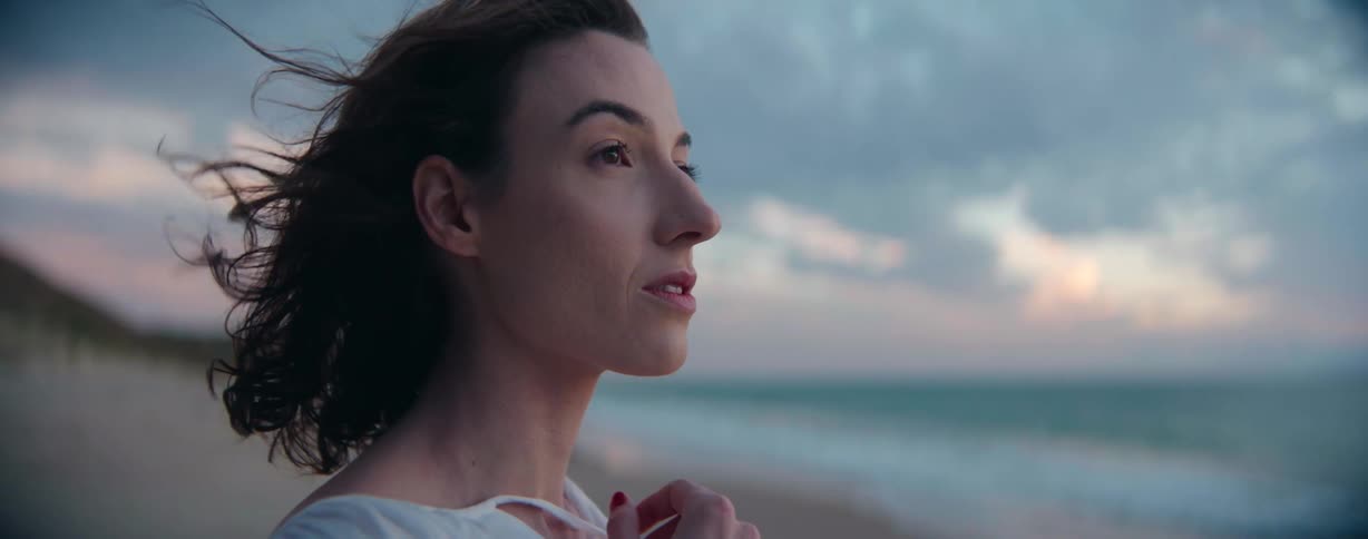 A female looking out over the ocean blinking her eyes
