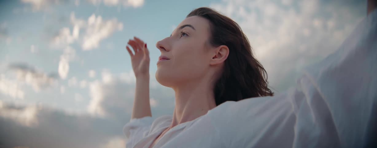 A woman stretches her arms out while looking up