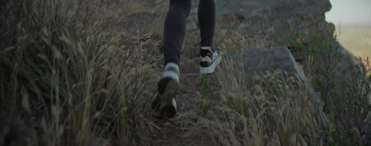 A woman hikes towards the edge of a cliff