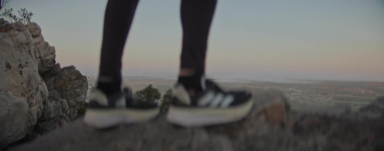 Legs of a person climbing a rock on a mountain with a panoramic view