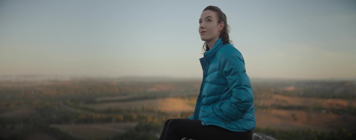 Woman sits on stone perch looking at the landscape