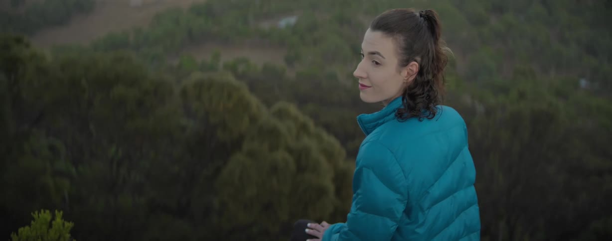 Woman with facial expression of happiness on a hill with trees