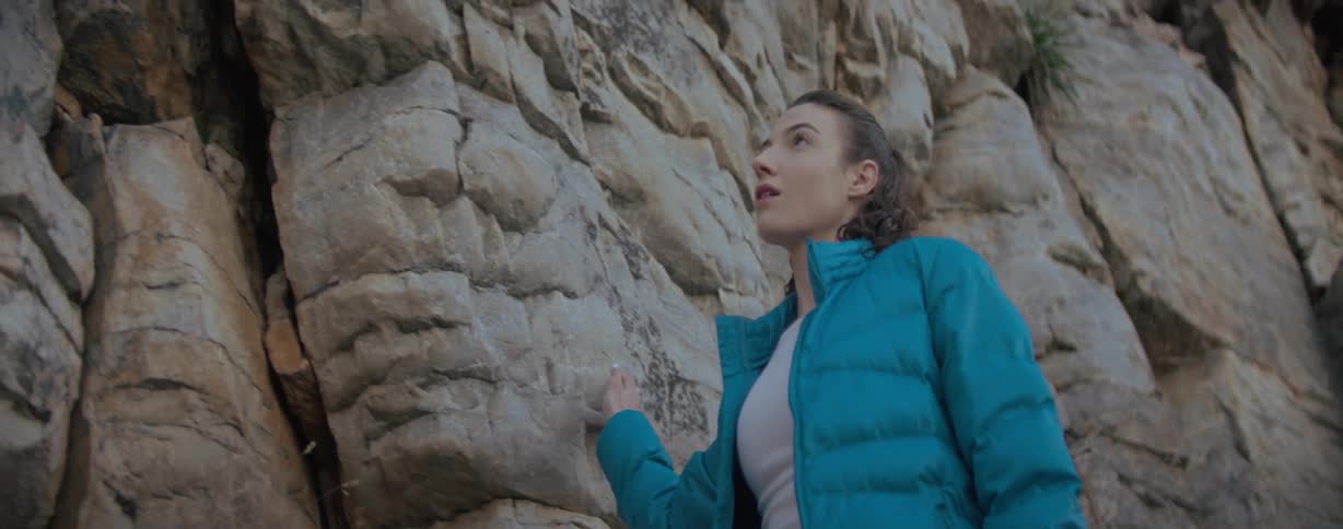 Woman skimming her hand across rock formations on a hiking trail