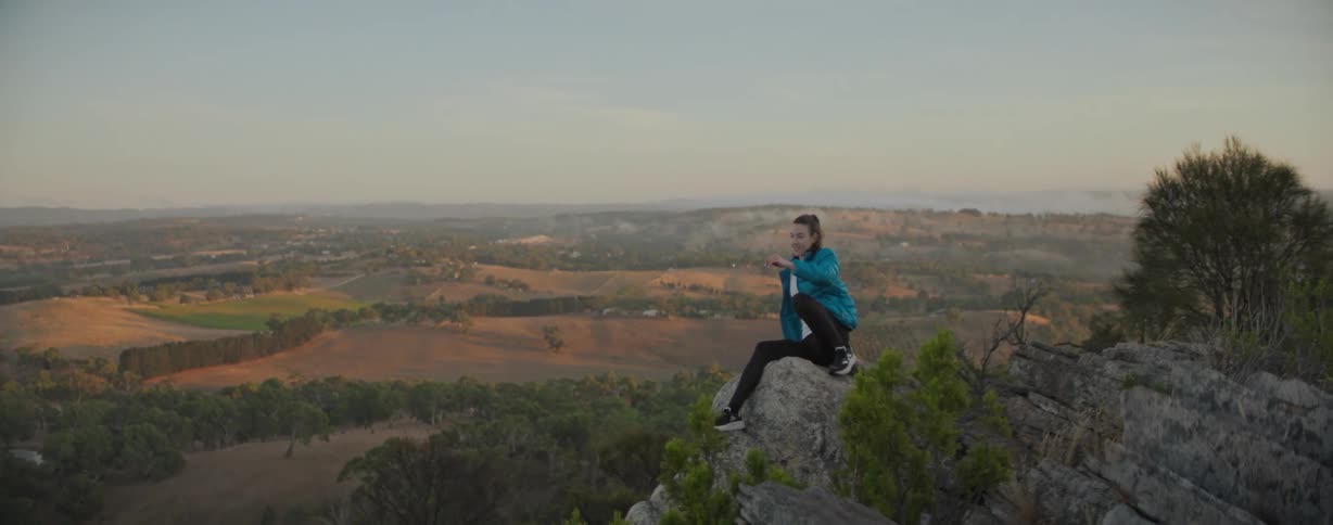 A woman sits on the edge of the mountain top