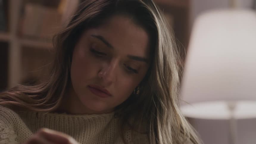 A young woman is reading something and then turns the page and is paying attention