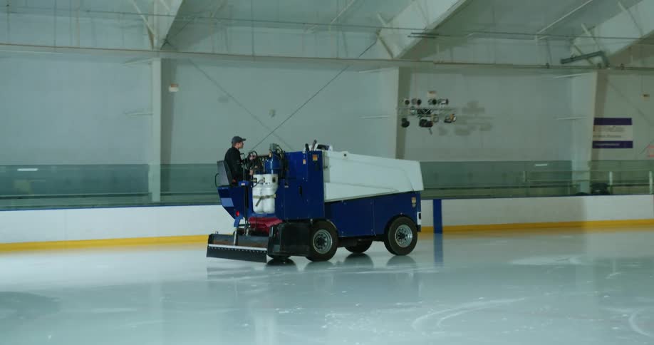 A man driving a zamboni to smooth the ice after hockey practice