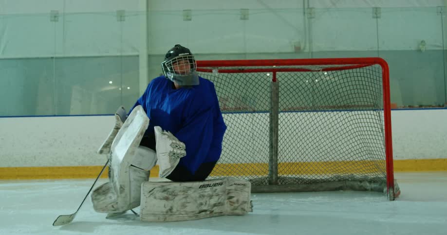 A goalie moves left to right practicing on a hockey ice ring