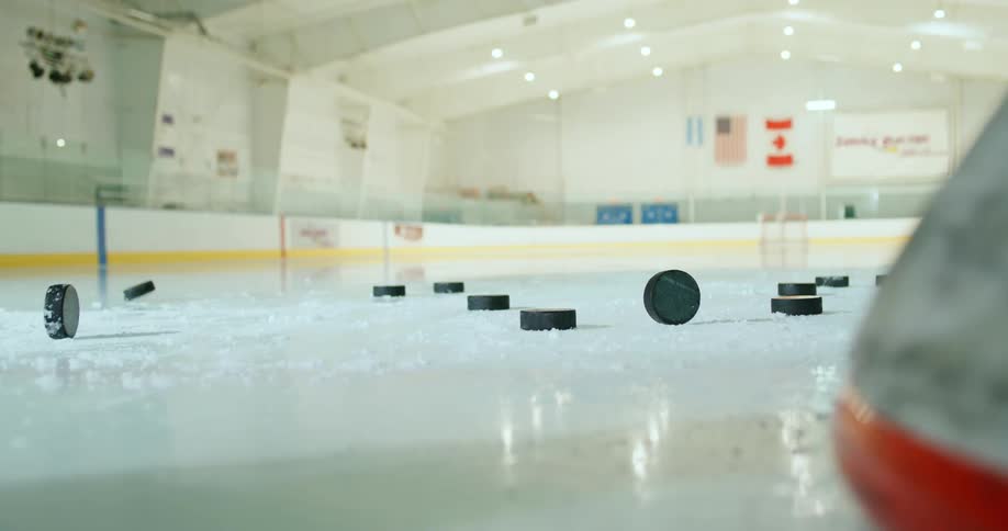 Hockey pucks falling on the ice rink