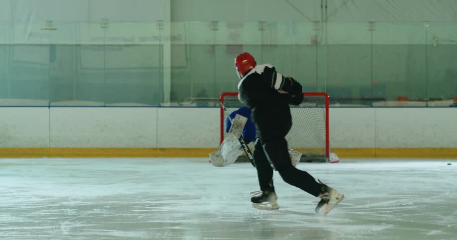 A hockey player takes a shot at the goal on an ice rink