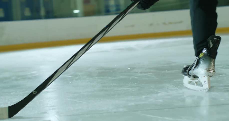 Player with a stick driving a puck towards the goal in a game on a hockey court