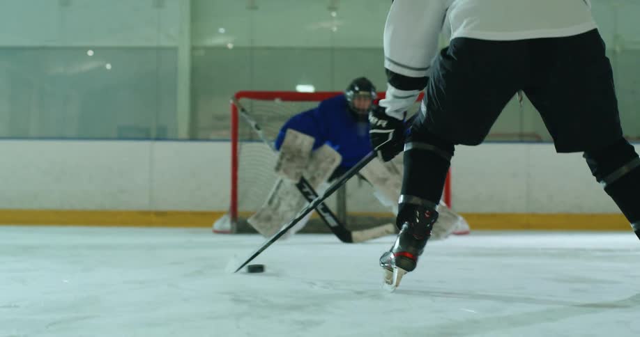 Hockey puck being driven by a player towards the goal on an ice court